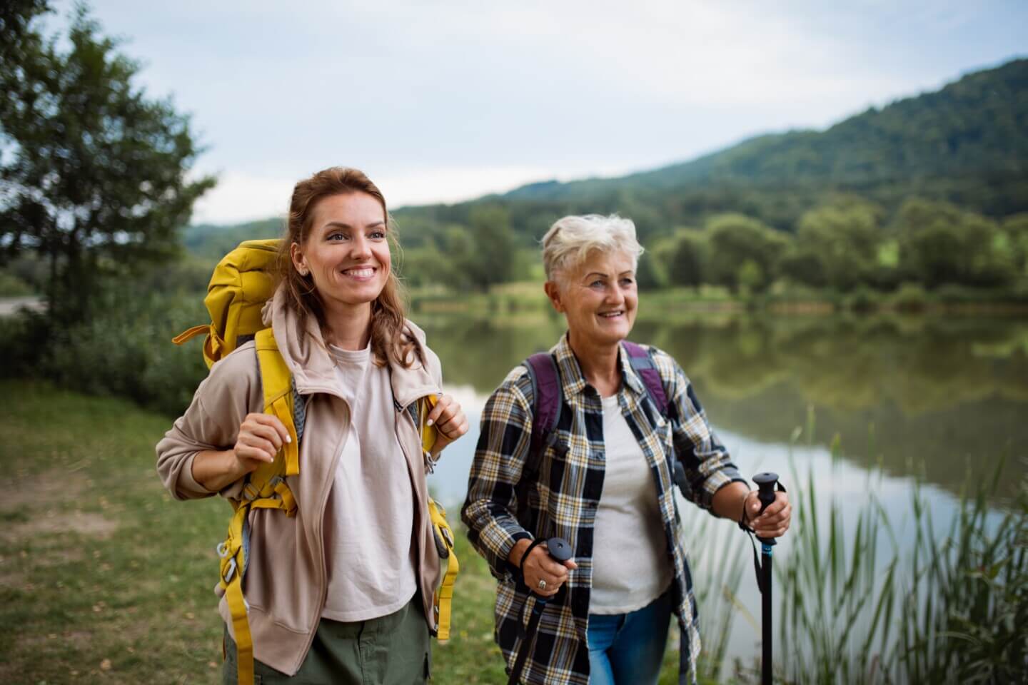 Happy-healthy-senior-woman-with-trekking-poles-and-companion-hiking-1440x960