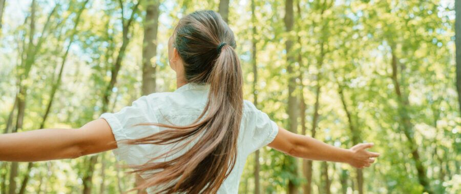 Happy Woman In Forest With Open Arms From Behind