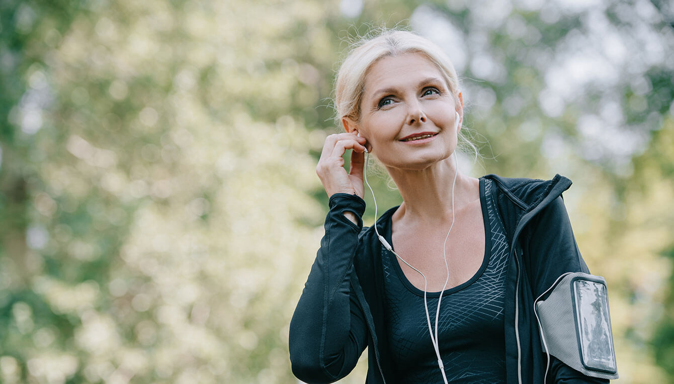 Recovering gut health patient listens to a podcast while exercising outdoors.