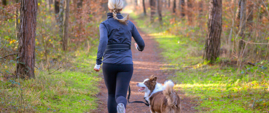 Woman running outdoors with her dog after finding relief to gut issues with supplements.