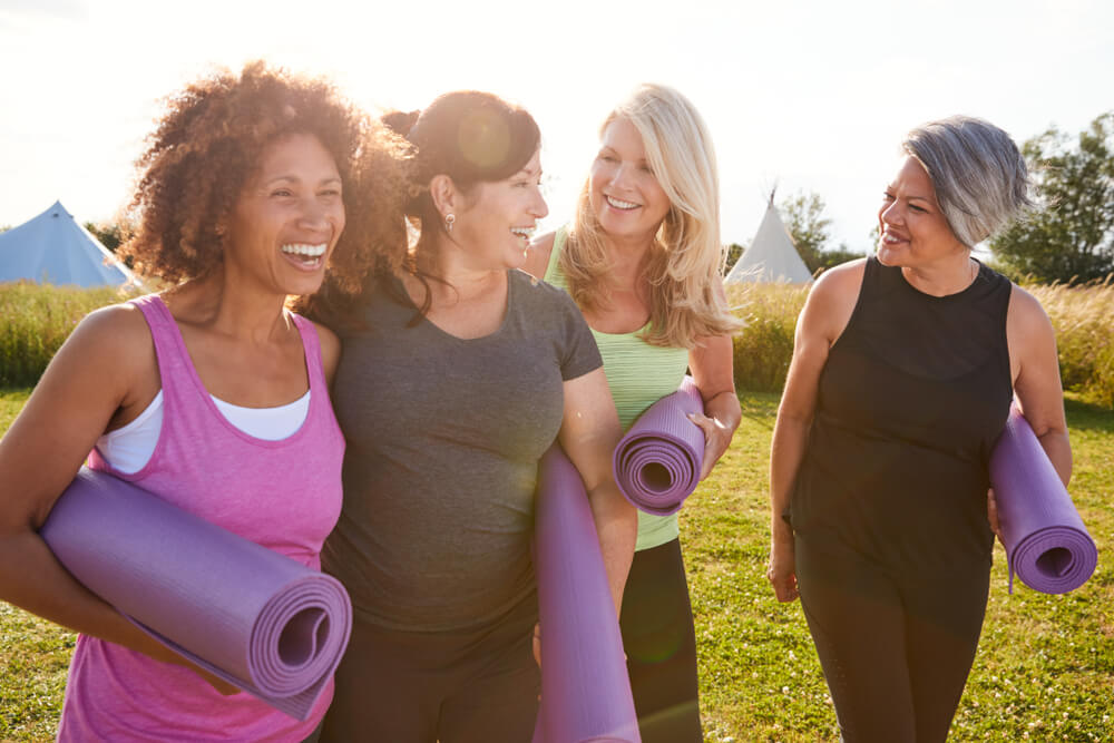 Group of mature women take yoga class outdoors having improved their hormone function during menopause