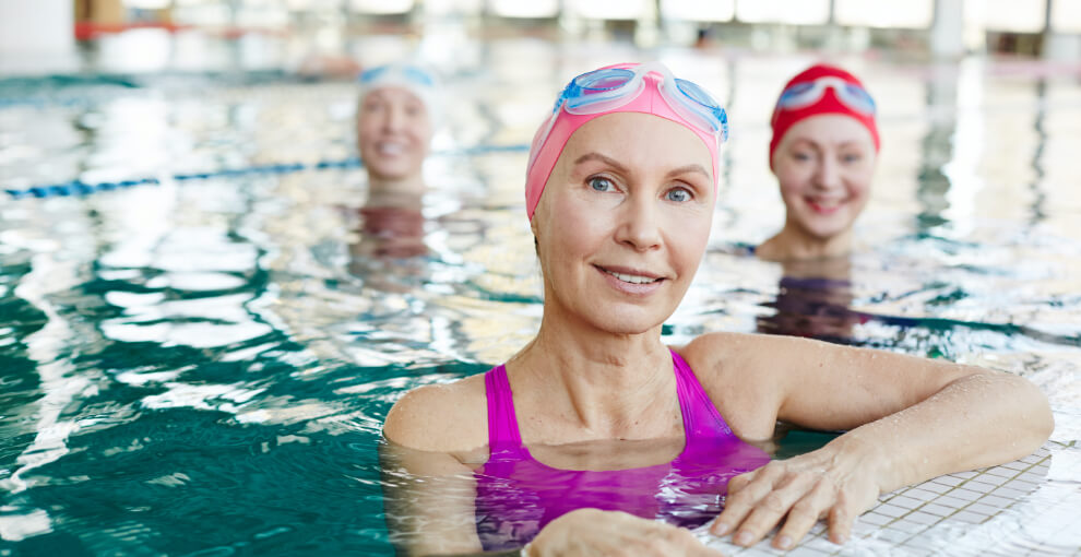 Three women in a pool with caps and goggles.