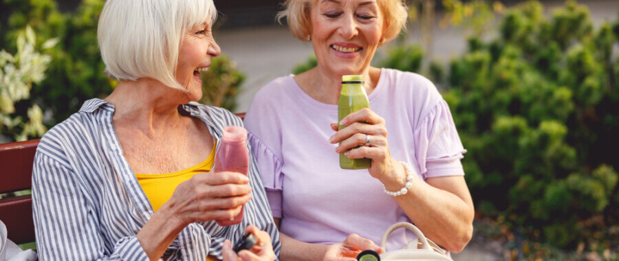 women drinking smoothie on bench