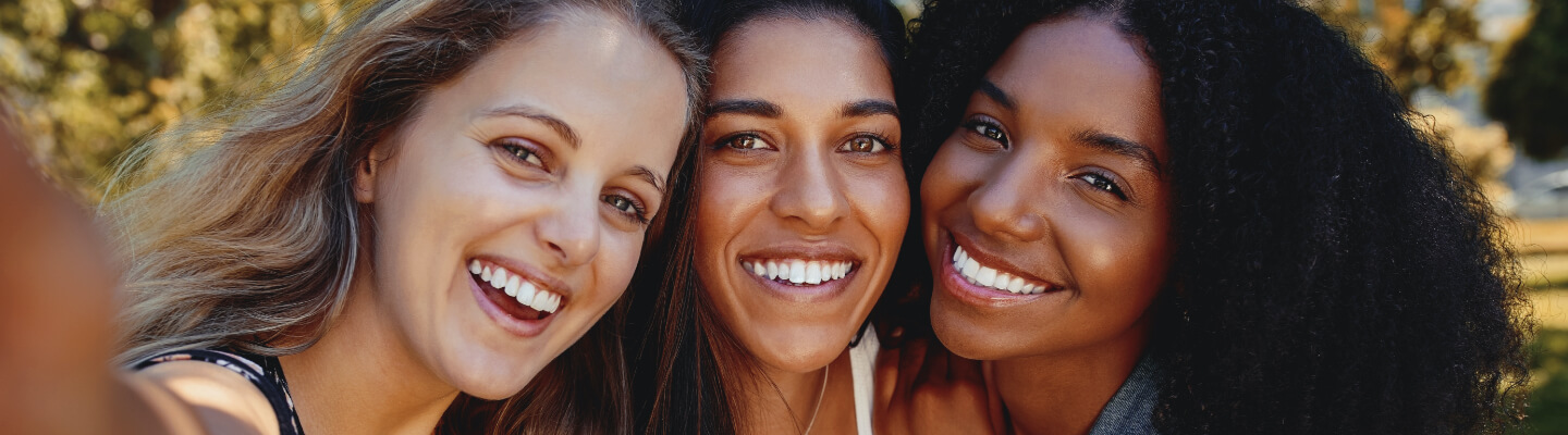 Three smiling women pose for selfie.